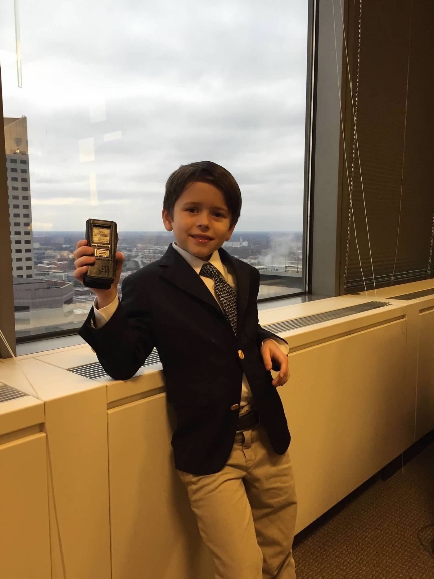 A young Jack Hamilton in a suit, holding a voice recorder downtown